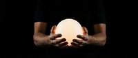 Male hands with medium-dark skin tone holding glowing sphere against black background. Isolated design element suitable for mysticism, fortune telling, energy, spirituality, and future prediction concepts.
