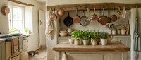 Rustic farmhouse kitchen interior with wooden countertops, hanging copper pots, herb plants and vintage cookware creating cozy country home atmosphere.