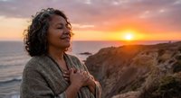 Mature African American woman enjoying peaceful sunset moment on coastal cliffs, expressing gratitude and inner peace during golden hour meditation.