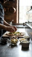 Male chef preparing homemade pizza with fresh toppings in rustic kitchen with brick wall background for culinary and cooking content.