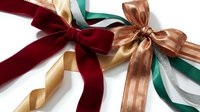 Colorful satin ribbons in burgundy, gold, copper, green and cream tied in elegant bows isolated on white background for gift wrapping and crafts.