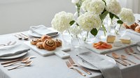 Elegant white table setting with fresh hydrangea centerpiece, pastries and cheese platter for special occasion dining and entertaining events.