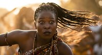 African woman with dreadlocks in motion during golden hour sunset, traditional jewelry and clothing, dynamic hair movement in warm natural light.