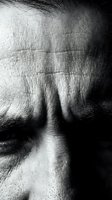 Close-up black and white portrait of mature man's forehead showing deep wrinkles and facial lines with dramatic lighting and shadows for aging concepts.