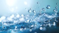Fresh water splash with crystal clear droplets creating dynamic motion against blue background with bokeh light effects and macro details of liquid surface.