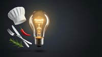 Culinary creativity concept with glowing light bulb, chef hat, fork and knife with herbs on dark background for cooking innovation and recipe development.