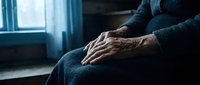 Elderly woman hands folded on lap sitting by window in contemplative moment. Aging, solitude, reflection, senior care, mental health concept.
