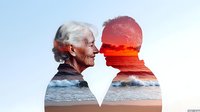 Senior Caucasian couple silhouette with double exposure effect showing ocean waves and dramatic red sunset, representing love, aging together and lasting romance.