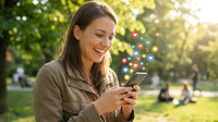 Happy young woman using smartphone in sunny park with bokeh lights, smiling while texting outdoors during golden hour for social media and communication.