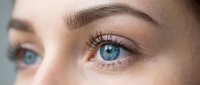 Close-up portrait of young woman with striking blue eyes and natural makeup showcasing detailed facial features and skin texture for beauty concepts.