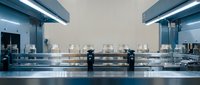 Modern laboratory interior with stainless steel equipment and glass containers under fluorescent lighting for scientific research and medical testing.