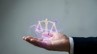 Businessman hand holding glowing purple scales of justice with magical sparkles for legal services and law firm concepts.
