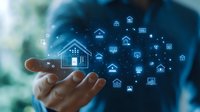 Digital smart home automation concept with glowing house icons floating above male hand against blue technology background for real estate solutions.