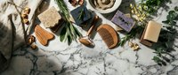 Organic skincare and wellness products arranged with fresh herbs and natural ingredients on marble surface for spa and beauty routines.