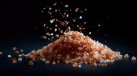 Pink Himalayan salt crystals scattered on dark background with floating particles, dramatic lighting creates gourmet culinary atmosphere.