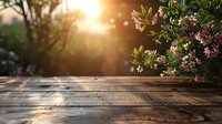 Rustic wooden table in garden with blooming pink flowers and golden sunset light creating warm atmosphere for outdoor dining.