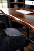 Modern workspace featuring natural edge walnut desk with rich wood grain texture and black upholstered office chair, highlighting contemporary minimalist design.