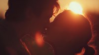 Silhouette of loving couple embracing at golden sunset creating romantic warm atmosphere for wedding anniversary valentines day greeting cards.