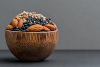 Wooden bamboo bowl filled with mixed nuts and dried berries on dark background, healthy organic superfood snack for nutrition and diet.
