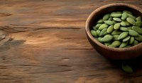 Fresh raw green pumpkin seeds in wooden bowl on rustic dark wooden table background with copy space for healthy food concept.