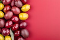 Fresh yellow and red plums arranged on vibrant red background with copy space, top view. Seasonal fruits composition for healthy eating concept.