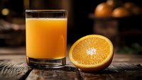 Fresh orange juice in glass with sliced orange half on rustic wooden table. Healthy breakfast drink with citrus fruit for morning nutrition and vitamin C.