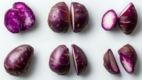 Fresh purple potatoes cut in halves showing vibrant magenta flesh isolated on white background, arranged in rows for food photography and culinary design.