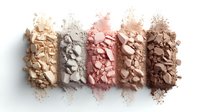 Crushed makeup powder swatches in nude and neutral tones arranged in rows showing texture and pigmentation on white background, cosmetic product flatlay.