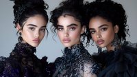 Three young women with natural curly hairstyles and glamorous evening makeup wearing black and purple sequined gowns pose together against light background.