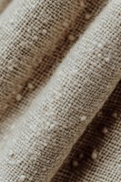 Natural linen fabric texture with diagonal fold creating soft shadows, close-up macro shot showing detailed weave pattern in neutral beige tones.