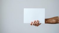 Cropped view of male hand with medium skin tone holding blank white card against neutral background, suitable for advertising, branding, marketing campaigns, and promotional materials.