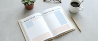 Open daily planner notebook with today's plan pages, coffee cup, glasses, and succulent plant on white desk for productivity and organization.