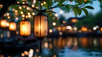 Glowing paper lantern hanging from tree branch over water reflection at dusk, with soft bokeh lights creating magical evening atmosphere. Perfect for mood setting.