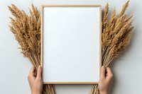 Hands holding wooden frame with dried pampas grass on white background. Minimalist mockup for artwork, prints and typography presentation.