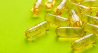 Golden yellow vitamin capsules scattered on bright green background for health and wellness supplement marketing materials.