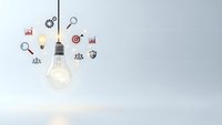 Glowing light bulb with business icons floating around representing innovation, creativity, strategy and growth concepts for corporate presentations.