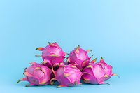 Fresh dragon fruit arranged in group on blue background, vibrant pink exotic pitaya with green leaves showing natural tropical produce.