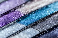 Colorful glitter eyeshadow palette with purple, blue, silver and black shades for makeup and beauty applications.