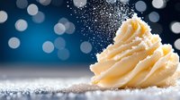 Creamy swirled buttercream frosting with powdered sugar dusting against bokeh lights background for baking and dessert concepts.