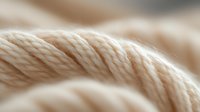 Twisted natural cotton rope macro shot showing detailed fiber texture and weave pattern in beige neutral tones, suitable for craft and textile backgrounds.