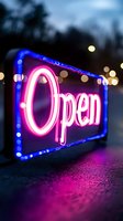 Glowing pink neon open sign with blue border against dark background, illuminated bokeh lights creating atmospheric night business ambiance.