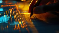 Financial analyst working with digital market data visualization and graphs, making notes during stock market analysis in dramatic orange-blue lighting.