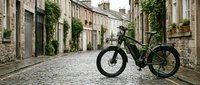 Modern electric mountain bike parked on cobblestone street lined with historic stone buildings and climbing ivy, suitable for urban commuting and outdoor adventure marketing.