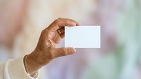 Senior adult with medium skin tone holding blank white business card for branding mockups, corporate identity presentations, and professional networking materials.