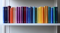 Row of colorful hardcover books arranged on white wooden shelf, spines showing rainbow spectrum from red to blue, creating modern minimalist library display.