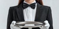 Female server in formal attire with black bow tie and white gloves holding silver serving tray, ready for upscale event service.