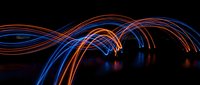 Abstract light trails in blue and orange flowing across dark background, suitable for technology, motion graphics, and digital design projects.