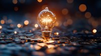 Glowing light bulb on wet surface with golden bokeh background creates magical atmosphere. Creative concept for innovation, ideas and inspiration.