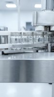 Glass jars on stainless steel conveyor belt in modern pharmaceutical manufacturing facility for sterile production and quality control processes.