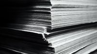 Stack of white paper sheets in black and white photography showing texture and layers for office and business documentation concepts.